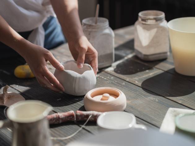 Close up of a woman making ceramic and pottery tableware at the workshop, working with clay and glaze