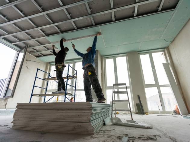 Construction worker assemble a suspended ceiling with drywall and fixing the drywall to the ceiling metal frame with screwdriver. Renovation, construction and do it yourself. High quality photo