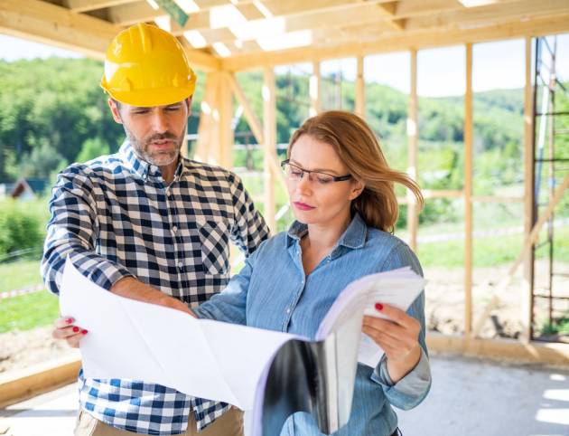 Female investor meeting with architect or engineer on construction site of her new house looking at blueprints