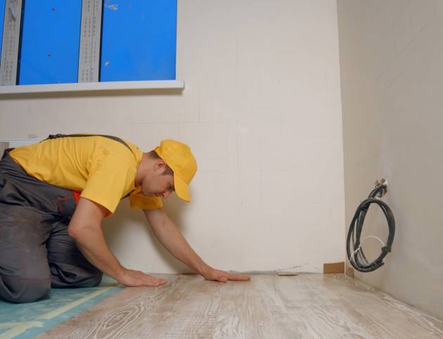 The master lays a new floor. Laying a wooden floor in a house.